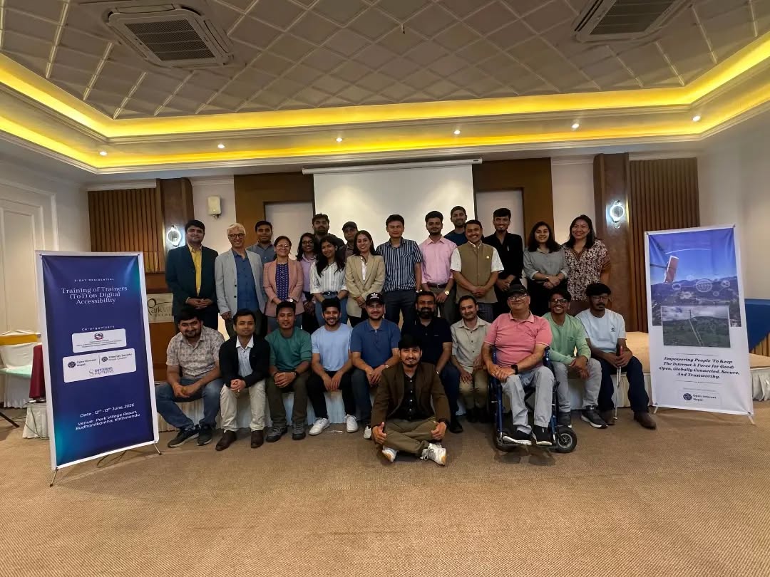 Group photo of attendees at a Training of Trainers on Digital Accessibility workshop, standing and sitting in a hotel conference room with event banners on either side.
